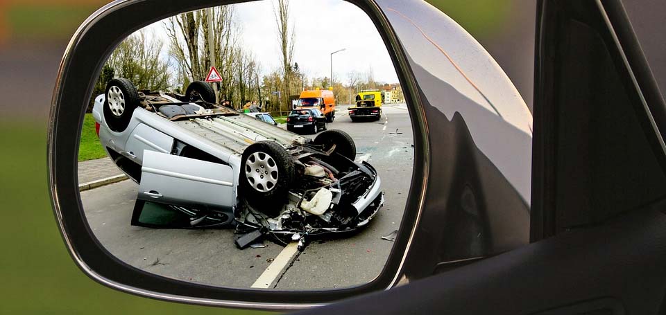 В зеркале заднего вида отражается перевернувшаяся в результате аварии машина